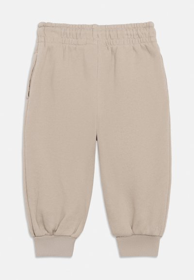 Beige sporta bikses ar elastīgu jostasvietu un ribotām aprocēm, ar sānu kabatām un gludu, mīkstu audumu.