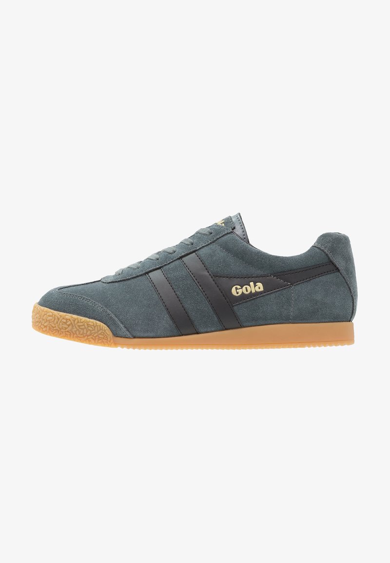 Sneakers Gola in suede grigio con strisce in pelle nera e logo dorato. Punta arrotondata e suola in gomma testurizzata. Stile atletico classico.