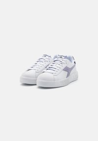 Baskets blanches en matériau synthétique, avec une touche lilas, bout rond, lacets plats et semelle en caoutchouc texturée avec un logo en relief.