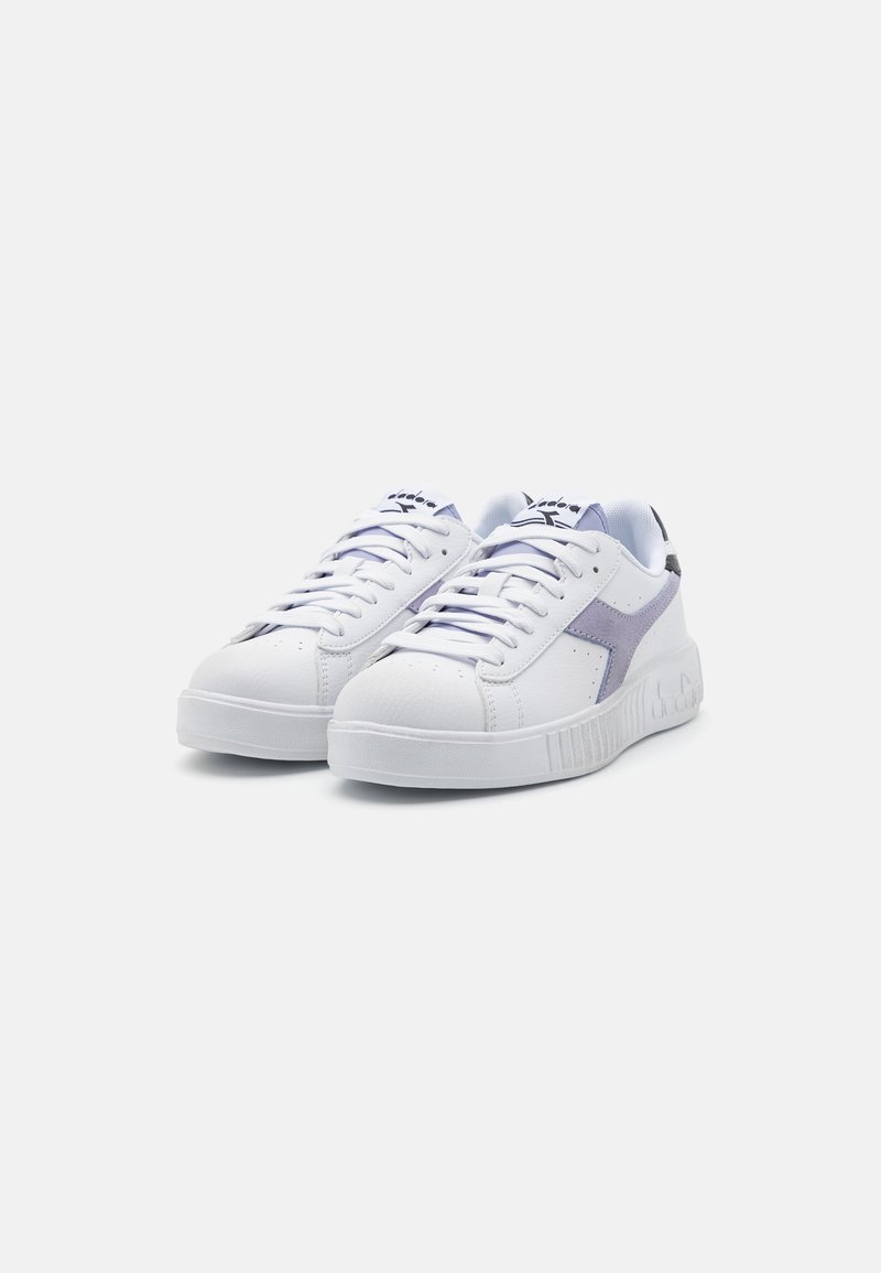 Sneaker bianche realizzate in materiale sintetico, con un'accensione lilla, punta rotonda, lacci piatti e suola in gomma testurizzata con branding in rilievo.