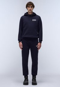 Marineblauwe hoodie met een voorzak en een trekkoord, gecombineerd met bijpassende joggerbroeken. Beide zijn gemaakt van zacht materiaal met subtiele branding.