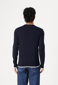 Pull en maille bleu marine à manches longues avec un col rond, des poignets et un ourlet côtelés, présentant une bordure contrastante au niveau du col.