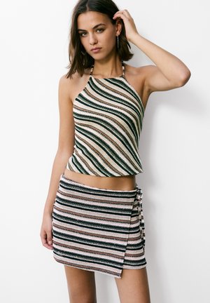 Pruhovaný pletený halter top a mini sukně v zelené, růžové a bílé barvě. Obsahuje volný střih s detaily na zavazování na boku sukně.