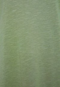 Tessuto verde chiaro che mostra una consistenza morbida e liscia con sottili variazioni di tonalità e un leggero motivo melangiato in tutta la superficie.