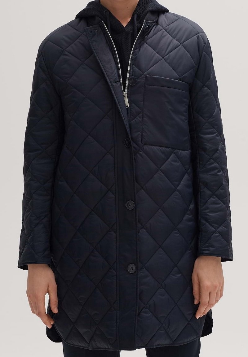 Abrigo azul marino acolchado con botonadura frontal, mangas largas y un bolsillo en el pecho. Confeccionado en un tejido suave y brillante, presenta un diseño con capucha.