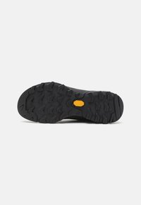 Čierna gumová podošva s hlbokými drážkami. Obsahuje žlté logo Vibram. Textúrovaný povrch pre lepšiu priľnavosť na rôznych terénoch.
