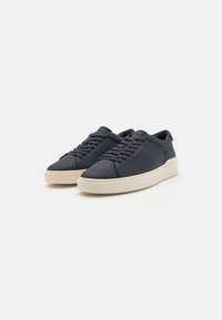 Marineblå lædersneakers med hvide gummisåler, der har flade snørebånd, perforerede sidepunkter og et minimalistisk design.