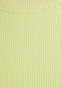 Tecido canelado numa suave cor verde pastel com riscas verticais. Textura lisa e uma borda cosida na parte superior.