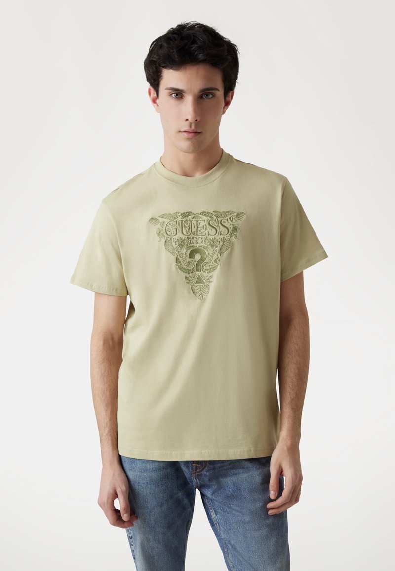 Šviesiai žalia medvilninė marškinėliai trumpomis rankovėmis su dideliu reljefiniu trikampio logotipo dizainu centre.