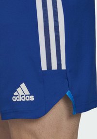 Blauwe sportshorts met witte gestreepte accenten aan de zijkanten, een zijsplit en een wit Adidas-logo aan de onderrand. Gemaakt van lichtgewicht materiaal.