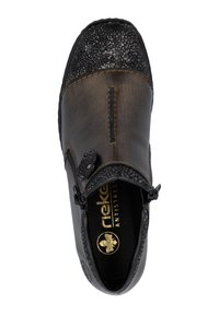 Chaussure en cuir brun avec un embout à motif noir, accent décoratif en forme de fleur et marquage doré "antistress" à l'intérieur. Fermeture zippée sur le côté.