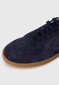 Tengerészkék nubuk bőr sneaker gumi talppal, lapos fűzőkkel, varrott részletekkel és márkázott logóval az oldalon.