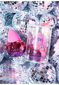 De beauty spons set bevat een roze spons met een glanzende, gefacetteerde basis en een doorzichtige container met sterrenpatronen en roze accenten.