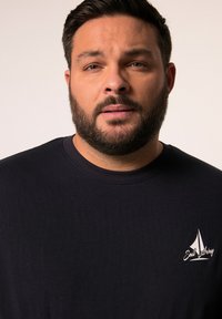 Černé bavlněné tričko s kulatým výstřihem, které má na levé straně hrudi malou grafiku bílé plachetnice a text "Sail Away".