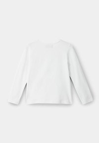 Long-sleeved white cotton top with a round neckline and side slits. Simple design with no visible patterns or accents.