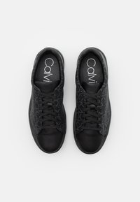 Baskets noires avec un bout mat lisse et une tige texturée présentant un motif géométrique. Les lacets sont placés au centre pour un ajustement sécurisé.