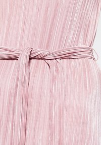 Helles pinkes, plissiertes Kleid aus Stoff mit einem passenden Stoffgürtel, der in einem einfachen Knoten an der Taille gebunden ist.