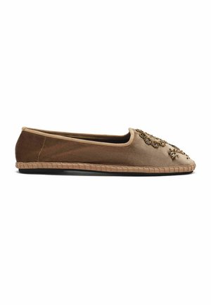 Chaussure plate marron avec des décorations en perles dorées sur l'avant et un bord de semelle en tissu, vue de côté sur fond blanc.