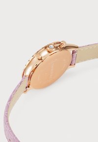 Orologio con cinturino in pelle rosa e cassa in oro rosa, caratterizzato da un chiaro accento di diamante sulla corona e una texture liscia sul cinturino.