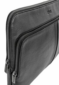 Czarna skórzana torba na laptopa z podwójnymi metalowymi suwakami, gładką fakturą i smukłym designem z wytłoczonym logo na przedzie.