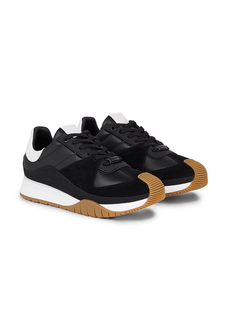 Sneaker nere con una combinazione di pelle e camoscio, dotate di una suola intermedia bianca e una suola esterna in gomma color miele. Lacci e dettagli in nero.