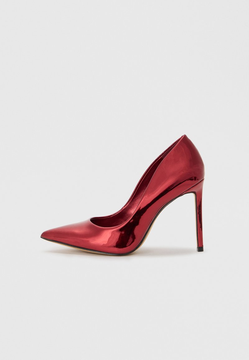 Rød lakk lær høyhælte pumps med spiss tå, slank silhuett og stiletthæl. Glanset overflate med minimale detaljer.