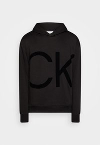 Sudadera negra con capucha y logo frontal en textura de felpa. Hecha de tela suave, con mangas largas y puños acanalados. Diseño simple y moderno.