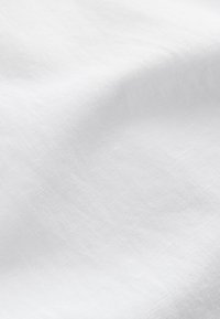 Tissu blanc lisse avec une texture douce et un motif de tissage subtil, délicatement drapé et plié.