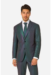 Iridescerend pak in donker groene en paarse tinten, met een strakke pasvorm, reverskraag, enkele knoopsluiting en voorzakken.