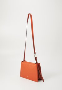 Oranga läder crossbody-väska med en texturerad yta, dragkedjestängning och en justerbar rem med en metallspänne.