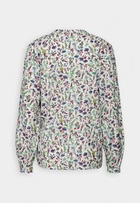 Blusa floreale bianca con maniche lunghe, caratterizzata da stampe botaniche colorate in verde, rosso e blu. Polsini arricciati e un semplice scollo rotondo.
