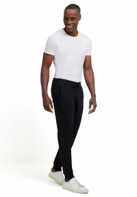 Witte t-shirt met korte mouwen, zwarte sweatpants met trekkoord en witte sneakers. Glad materiaal, casual pasvorm en minimalistisch ontwerp.