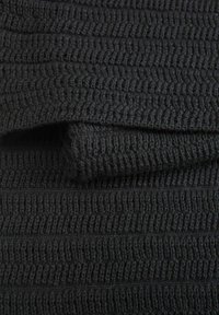 Musta struktuuripinta, jossa on vaakasuoria uria. Materiaali näyttää pehmeältä ja neulotulta, tarjoten mukavaa tunnelmaa.