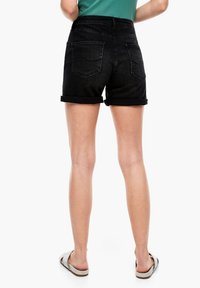 Černé džínové šortky s vysokým pasem, ohrnutými manžetami a dvěma zadními kapsami, které se vyznačují jemnou texturou a minimalistickým designem.