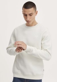 Witte sweatshirt met een ronde hals, ribgebreide manchetten en een zoom. Bevat een klein logo op de borst en heeft een gladde, zachte textuur.
