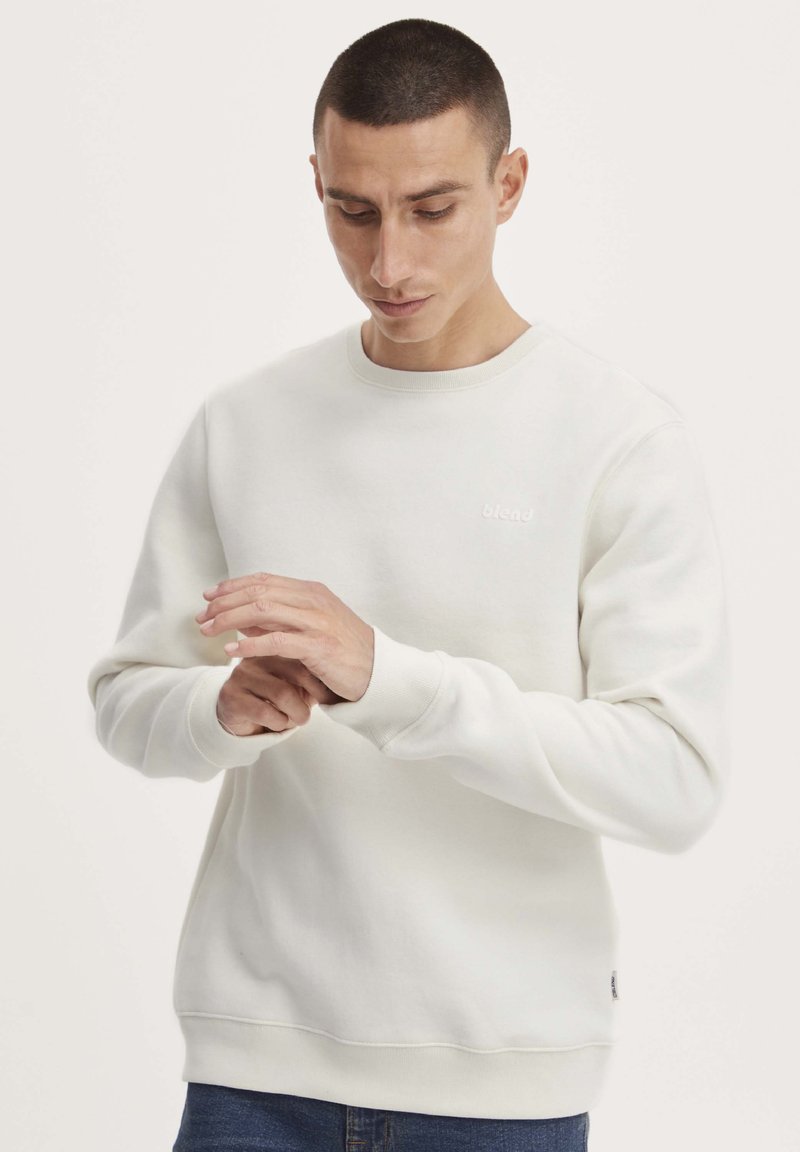 Witte sweatshirt met een ronde hals, ribgebreide manchetten en een zoom. Bevat een klein logo op de borst en heeft een gladde, zachte textuur.