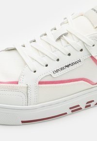 Valkoiset lenkkarit, joissa on vaaleanpunaisia yksityiskohtia, kangas- ja nahkamateriaalit, teksturoitu vuori, pyöreä kärki ja litteä kumipohja, jossa on logotagi.