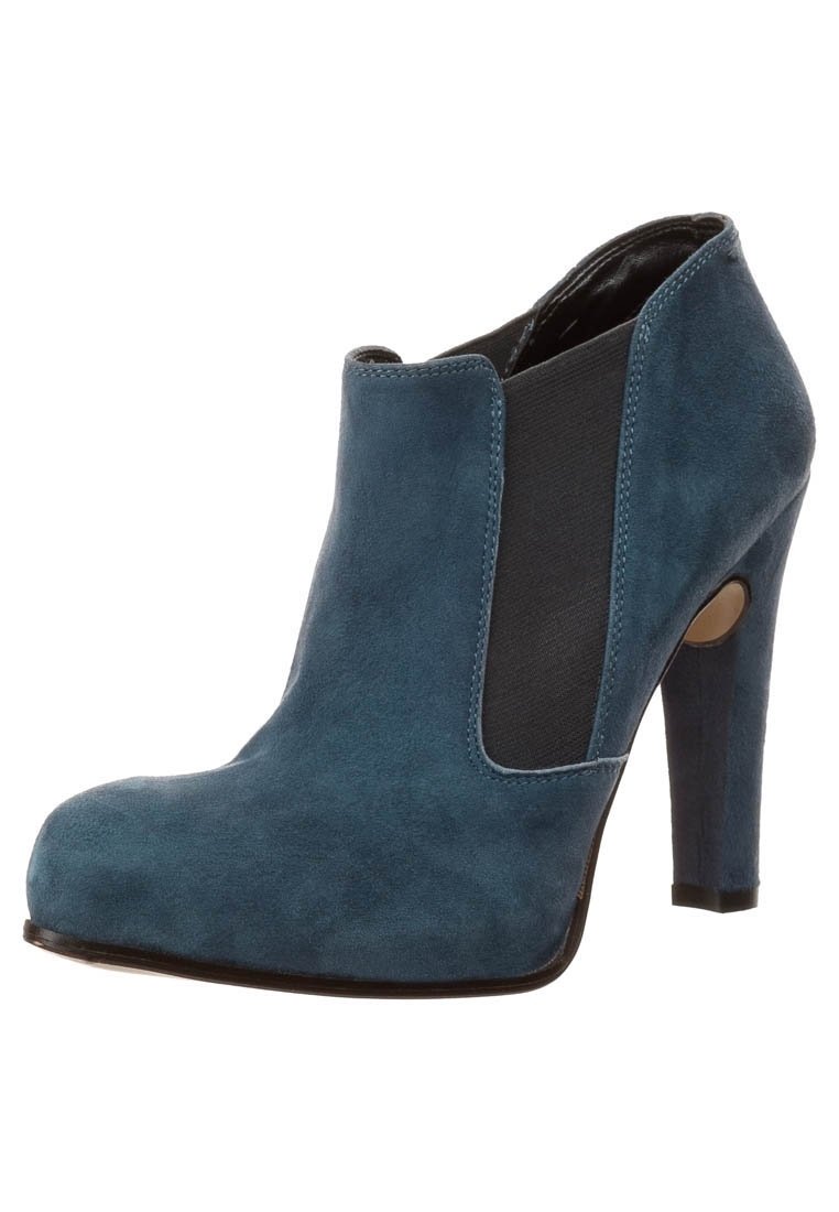 Sininen mokkanahkainen nilkkuri, jossa on korkea stiletto-korko, joustavat sivupaneelit ja pyöreä kärki. Suuret sileät pinnat, joissa on kontrastivärisiä mustia yksityiskohtia.