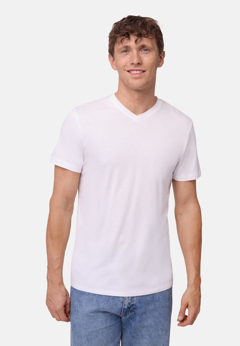 Weißes V-Ausschnitt-T-Shirt aus weichem Stoff, mit kurzen Ärmeln und figurbetontem Schnitt, getragen mit blauen Jeans. Einfaches und sauberes Design.