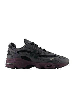 Sneaker atletico in nero e grigio con tomaia in mesh, linguetta imbottita e punta tonda. Presenta una suola intermedia viola e dettagli del logo in rilievo.