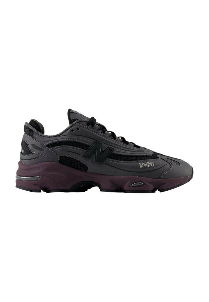 Baskets de sport noir et gris avec une tige en mesh, une languette rembourrée et un bout rond. Présente une semelle intermédiaire violette et des détails de logo embossés.