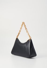 Black leather handbag with a structured shape, featuring a large gold chain handle and a top zipper closure. Smooth texture and minimal design.