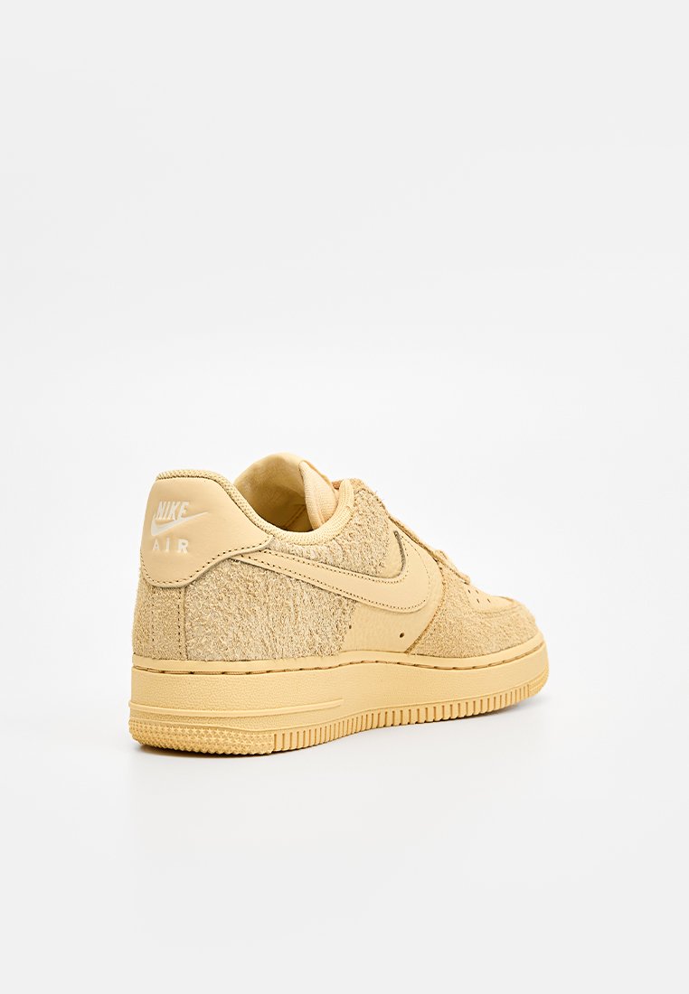 Baskets Nike Air beiges avec une tige en tissu texturé et des accents en cuir lisse. Comprend une semelle en caoutchouc et un logo en relief au niveau du talon.