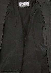 Schwarze Jacke mit einem glatten Satin-Innenfutter, mit einem Etikett, auf dem "Televen" steht. Das Design ist minimalistisch, ohne sichtbare Reißverschlüsse oder Taschen.