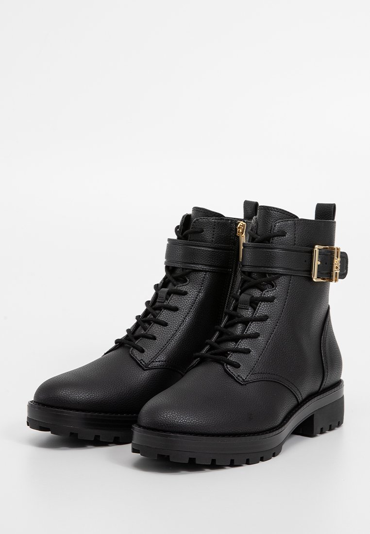 Schwarze Knöchelstiefel aus strukturiertem Leder. Merkmale sind eine Schnürung vorne, ein Seitenreißverschluss und ein goldener Schnallenakzent. Robuste Sohle.
