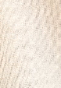Tissu beige clair avec une fine texture tricotée, présentant un motif uniforme de petits trous régulièrement espacés.