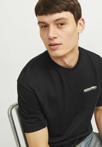 Sort bomulds t-shirt med rund halsudskæring og korte ærmer. Har et lille hvidt logo på venstre bryst. Blød tekstur.