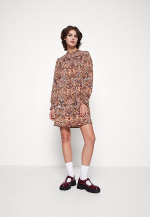 Pitkähihainen mekko, jossa on värikäs paisley-kuvio lämpimissä sävyissä. Kankaan pinta on sileä, ja mekoissa on hieman löysä istuvuus sekä rypytettyjä yksityiskohtia.