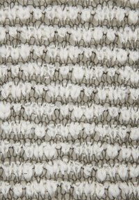 Vävt tyg med växlande vita och grå trådar i ett texturerat mönster. Tyget visar en blandning av öglor och öppna vävningar.