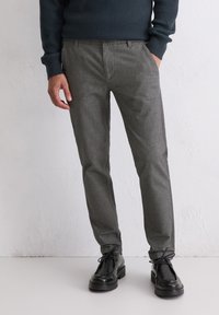 Szare spodnie w wzory o slim fit, wykonane z teksturowanej tkaniny. W po�łączeniu z czarnymi skórzanymi butami z detalem sznurowania.